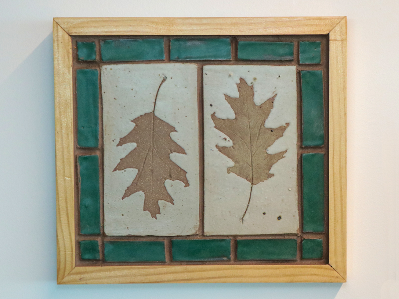 This small ceramic tile mural depicts two leaves, impressed in the clay. The leaves were collected from the woods behind our house. When I walk in the woods in the fall, I can hear the crunch of the dried fallen leaves beneath my feet. The tiles were fired in the high-fire gas kiln I’ve built in our backyard. Two leaves? I’m bi-lateral.